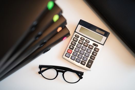 bureau de comptable avec calculatrice, relevé de compte immobilier et plans d'un immeuble pour calculer une plus-value